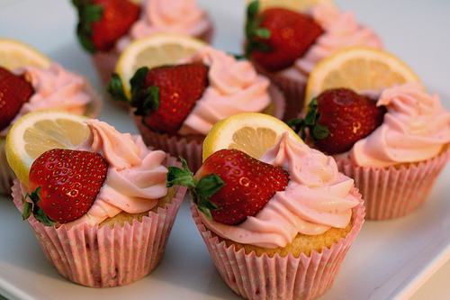 cupcakes with a strawbery and lemon on top with pink frosting